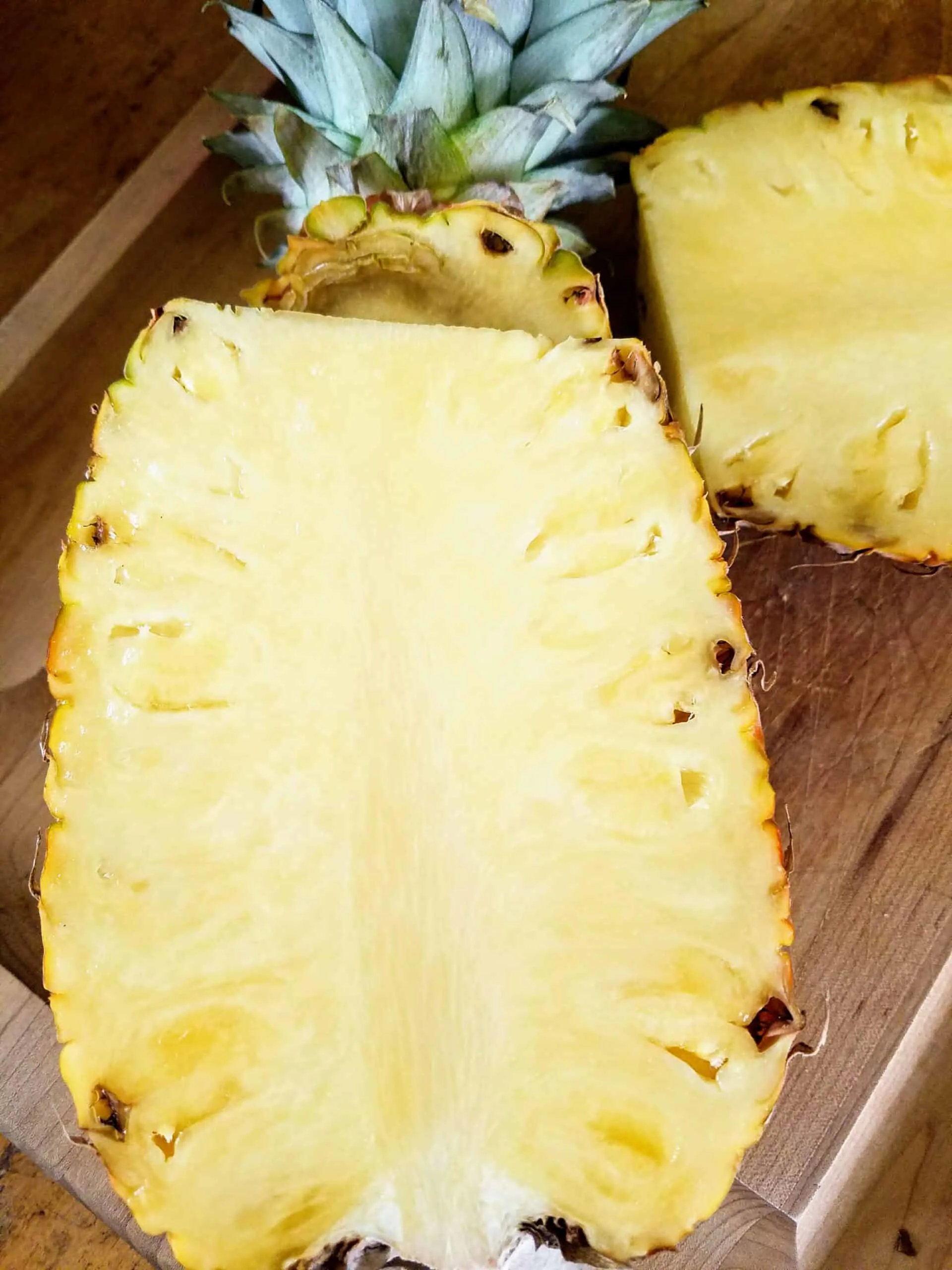 a half of a pineapple frshly cut on cutting board