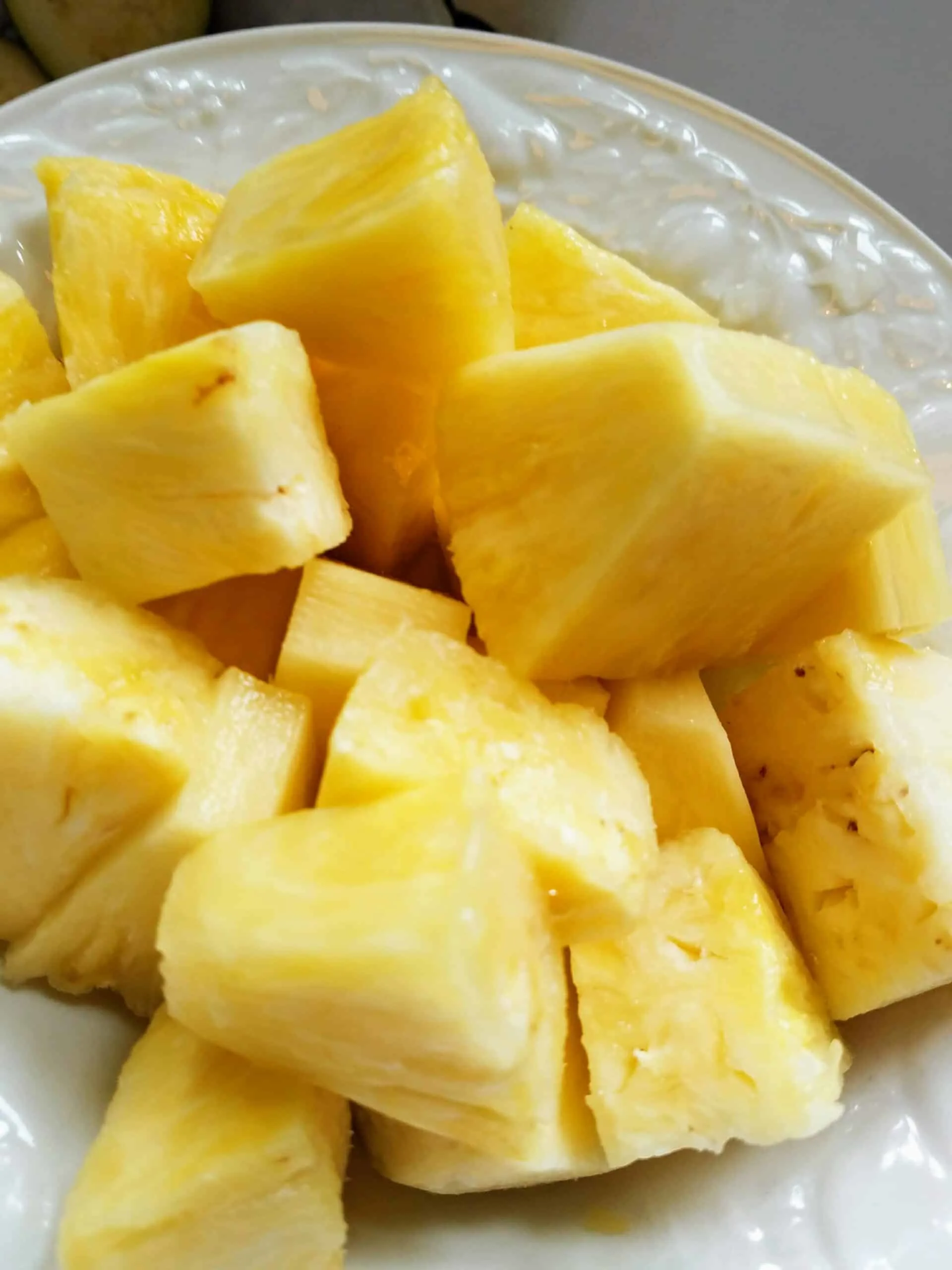 chunks freshly cut pineapple in a white bowl
