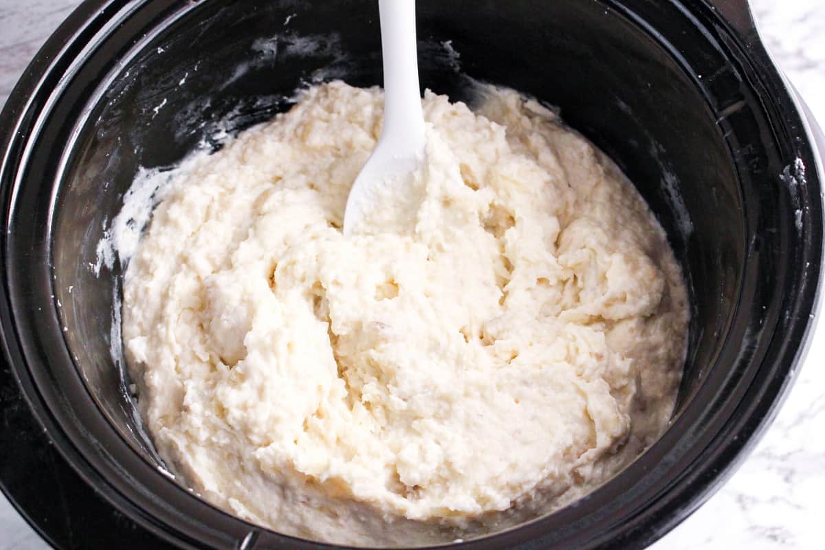 slow cooker mashed potatoes in crock pot ready to serve with white spoon