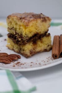 sliced honey bun cake plated with nuts and cinnamon sticks