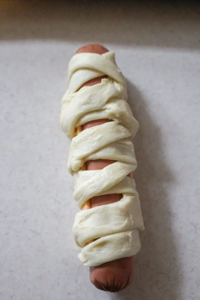 Mummy dough wrapped hot dog ready to be baked