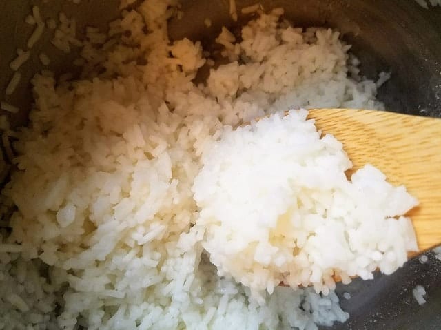 cooked jasmine rice in a pot with wooden spoon