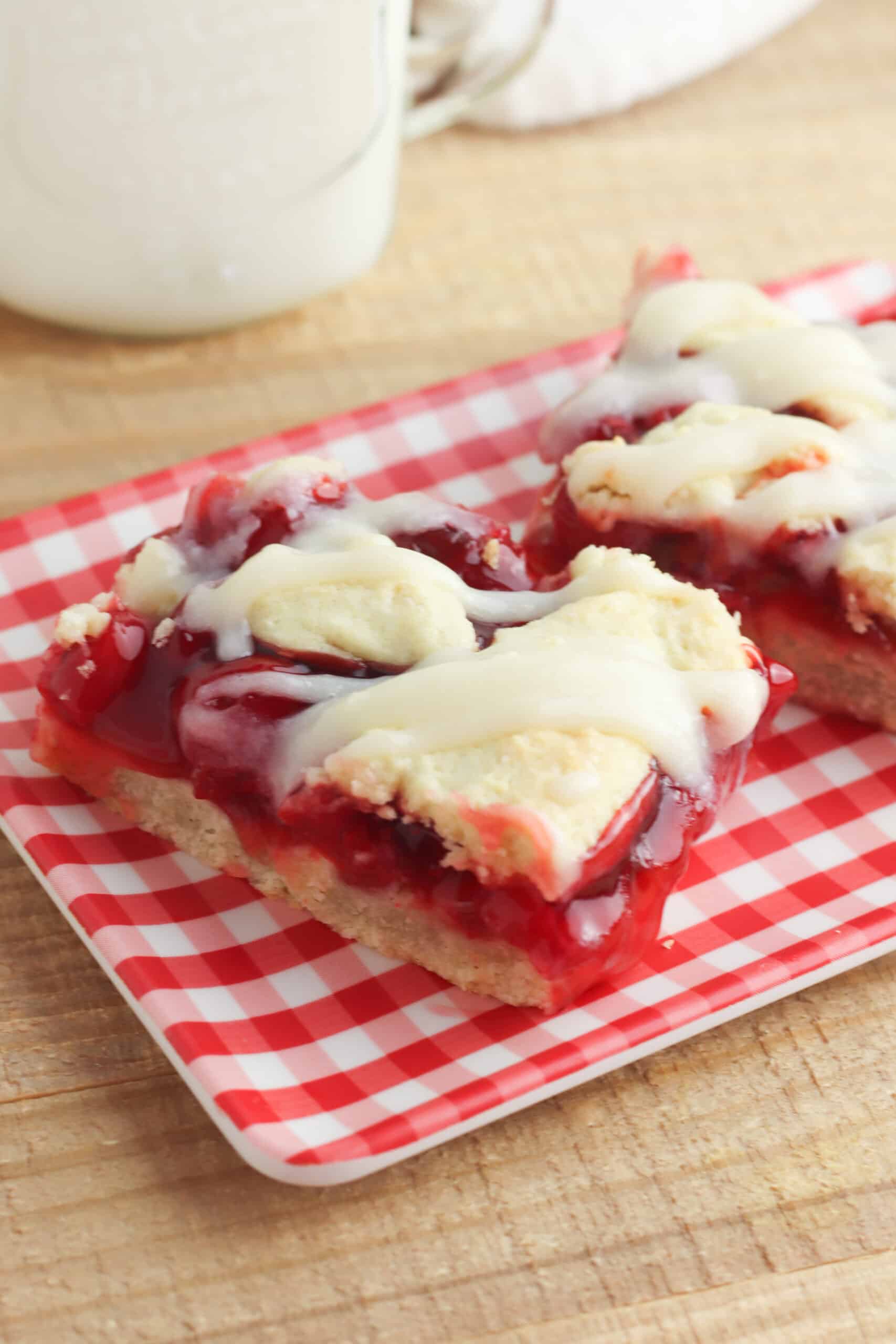 Cherry Pie Bars served on red and white checkered plate on a wooden table