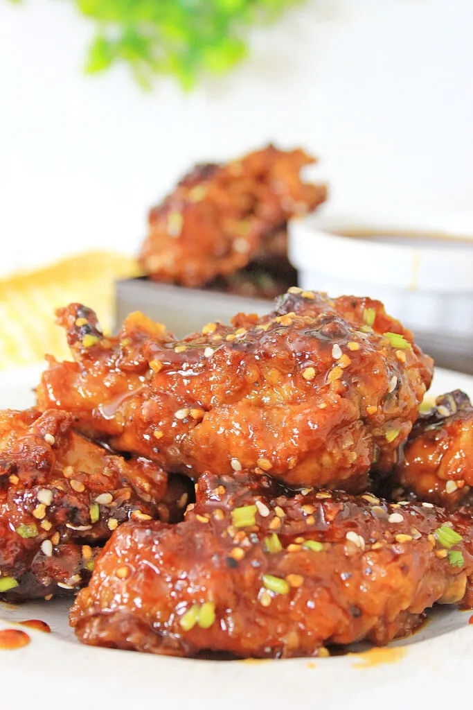 Air Fryer Korean BBQ Chicken Wings on a plate with drizzled sauce, sesame seeds and scallions