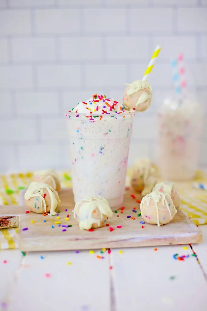 Copycat Starbucks Birthday Cake Frappuccino ready to drink on a board with sprinkled cake balls
