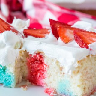 red white and blue flag poke cake sliced and served with red white and blue drizzle throughout the white cake