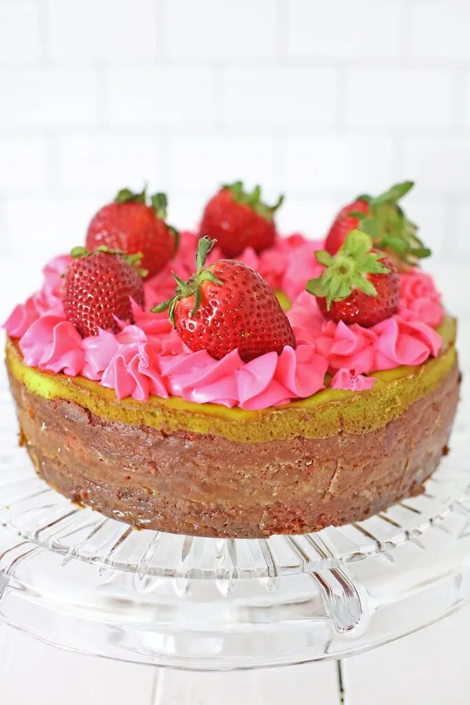 hero shot of complete key lime strawberry cheesecake decorated with frosting piped on and fresh strawberries.