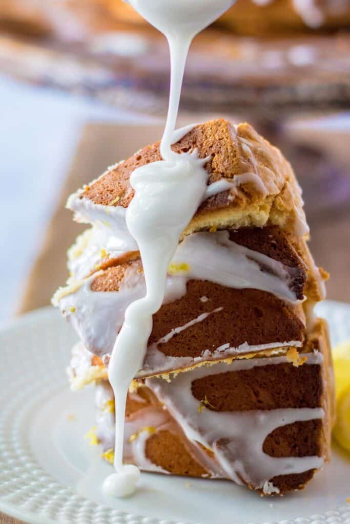 Lemon Cream Cheese Bundt Cake with glaze lemon zest over wooden board cake sliced with glaze poured on top