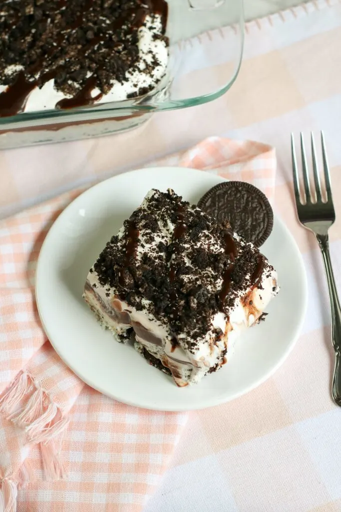 top view of a slice of no bake oreo cookie delight on a white plate, extra oreo cookie, fork