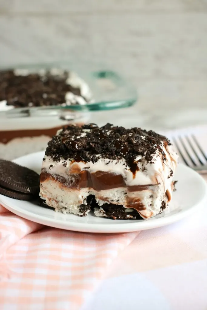 close up of no bake oreo cookie delight on a white dish with an oreo cookie on the side