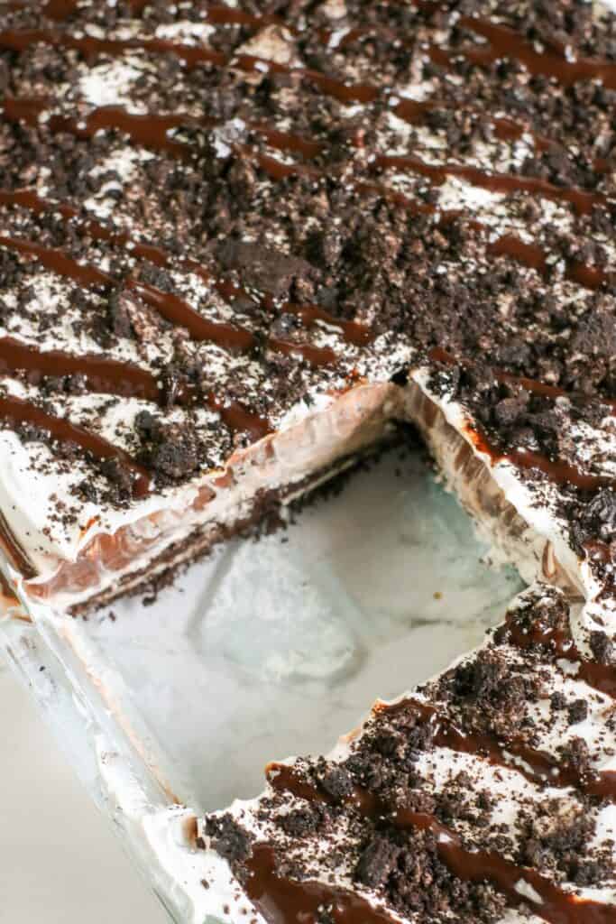 the inside of the no bake oreo cookie delight inside the casserole dish looking from on top of the chocolate dessert, one slice removed