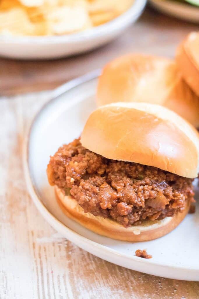 Sloppy Joe is ready to be bitten into served on a plate.