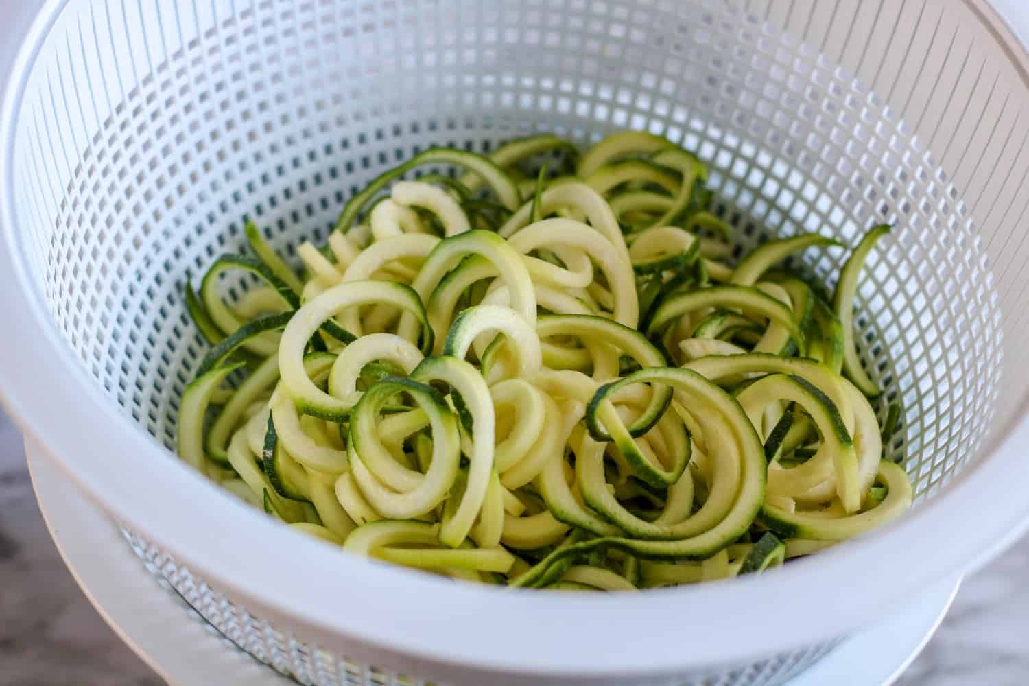 zucchini noodles, zoodles draining in a colander