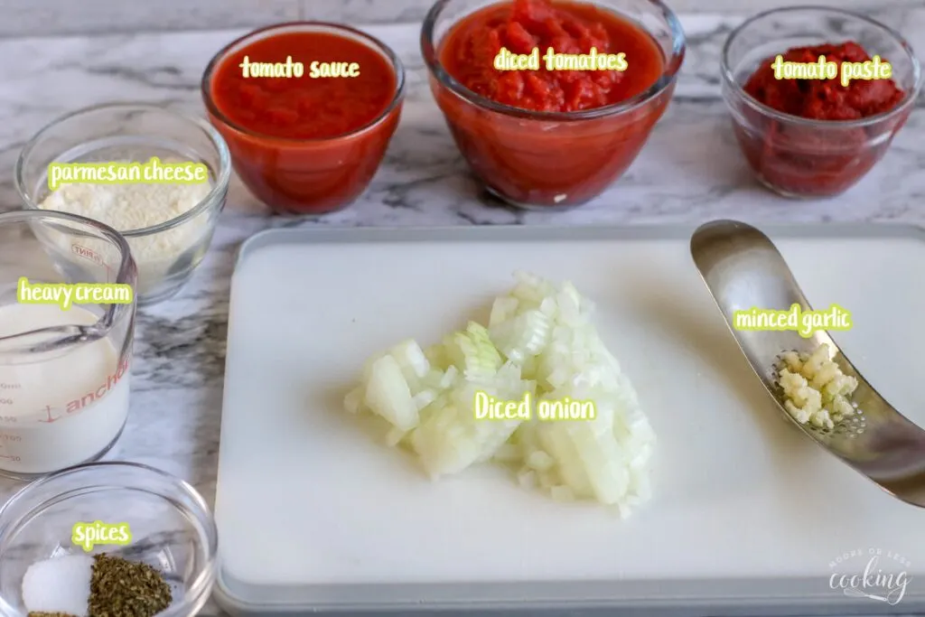 ingredients for spicy sausage and creamy tomato sauce over zoodles labeled in bowls and cutting board