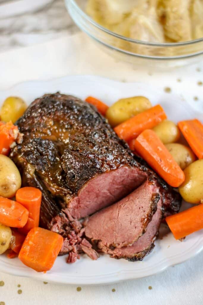 corned beef roast cooked, sliced carrots and potatoes served on platter