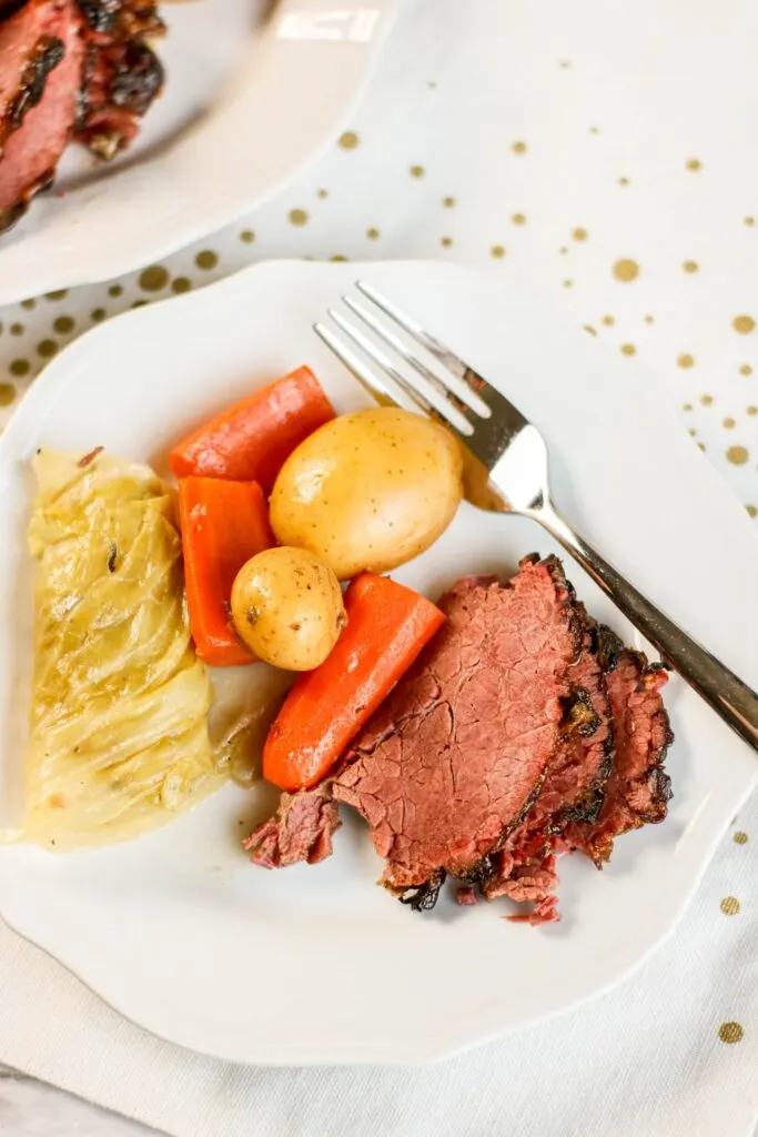 Three slices corned beef, cabbage, carrots and potatoes, served with platter and fork