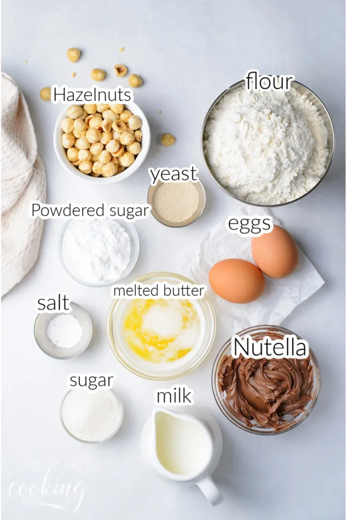 All of the ingredients set out to make one loaf of Nutella Hazelnut Wreath Bread in individual bowls, 10 ingredients