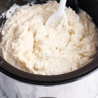 slow cooker mashed potatoes finished in slow cooker with spoon hero shot