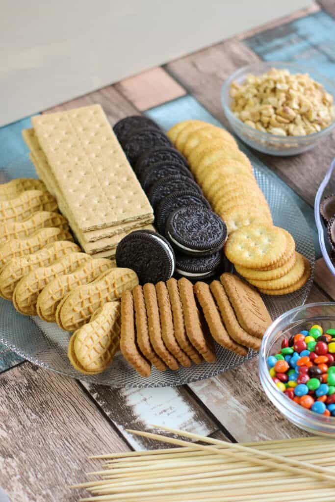 cookies, crackers, oreos, peanuts, nutter butters, all of the ingredients for S'mores Board laid out
