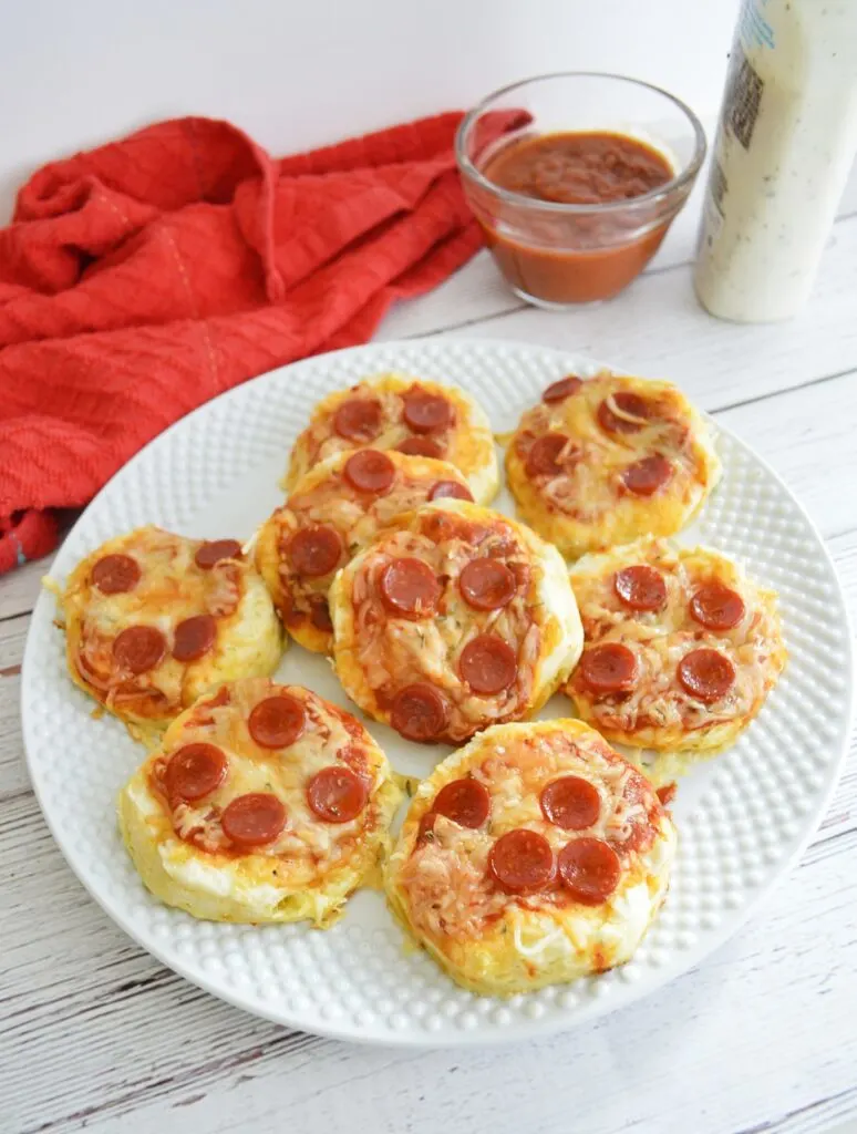 top shot mini pepperoni pizzas on white serving plate marinara sauce in bowl and ranch sauce red towel