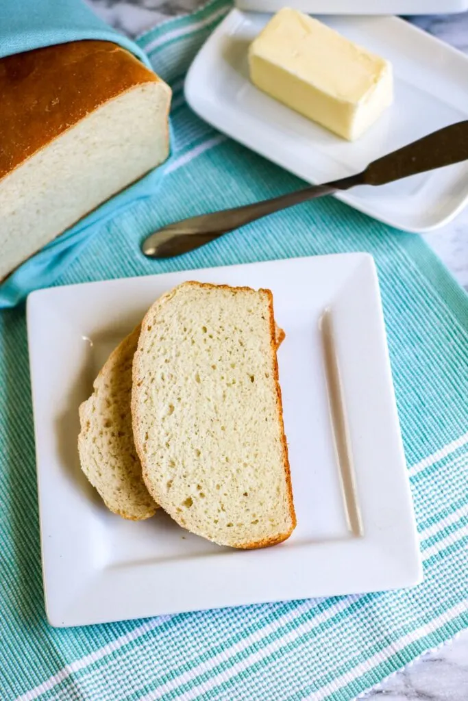 Bread in a bag hero vertical shot loaf cut 2 slices served butter dish butter knife on blue tablecloth