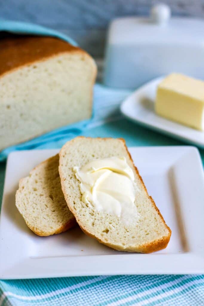 Bread in a bag vertical shot loaf cut served with pat of butter spread on bread slices butter dish on blue tablecloth