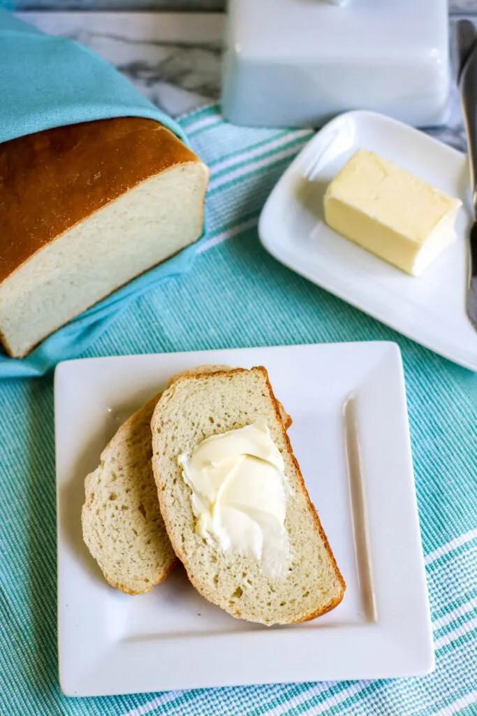 Bread in a bag  vertical shot loaf cut served with pat of butter butter dish on blue tablecloth