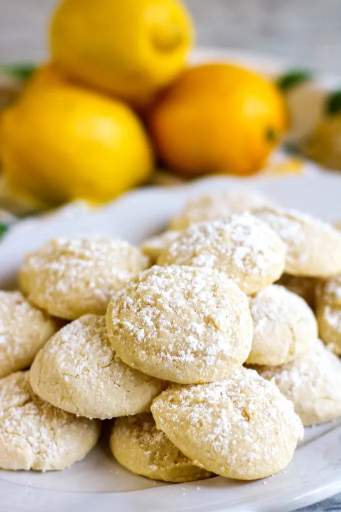 vertical shot hero Lemon Cookies on a platter with lemons