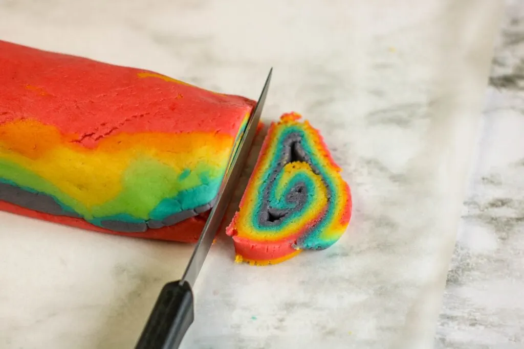 slicing rainbow swirl cookie dough with sharp knife