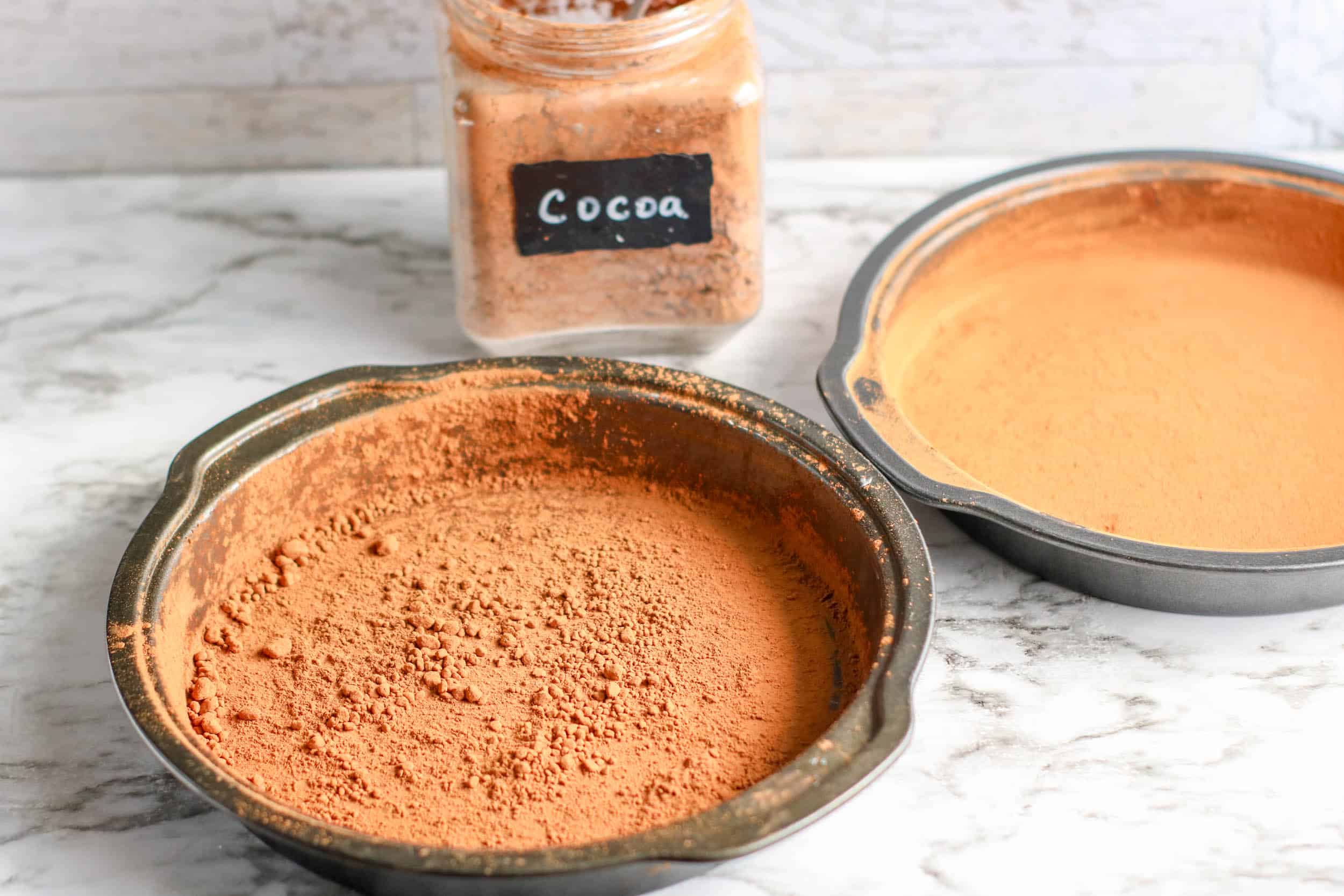 three 9-inch round cake pans by greasing and dusting with cocoa powder.