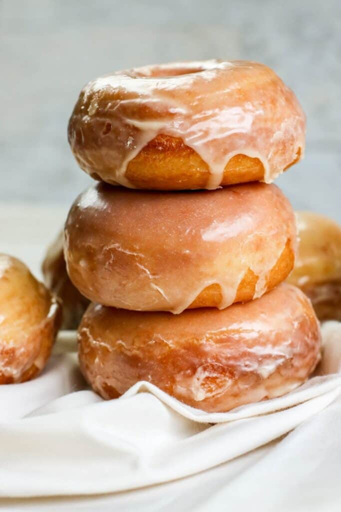 Homemade yeast doughnuts with a vanilla glaze hero stacked doughnuts vertical white cloth