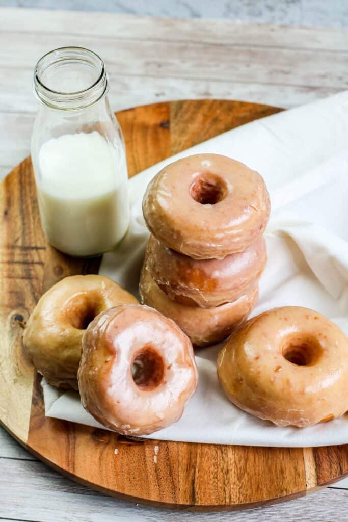 Homemade yeast doughnuts with a vanilla glaze hero stacked doughnuts with milk jug on wooden board white cloth
