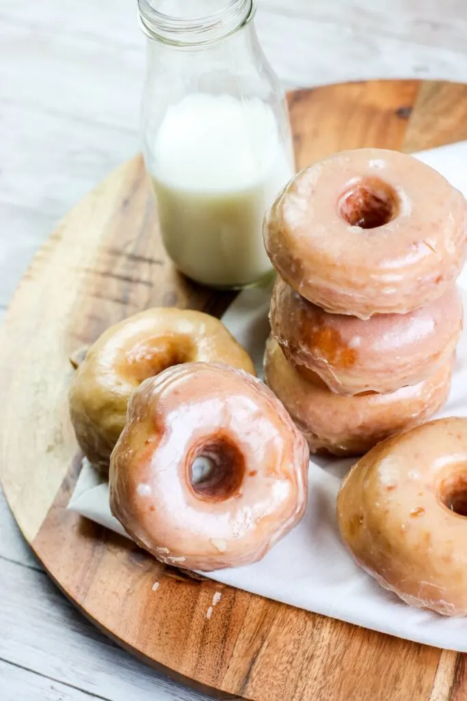 top shot Homemade yeast doughnuts with a vanilla glaze hero stacked doughnuts with milk jug on wooden board white napkin