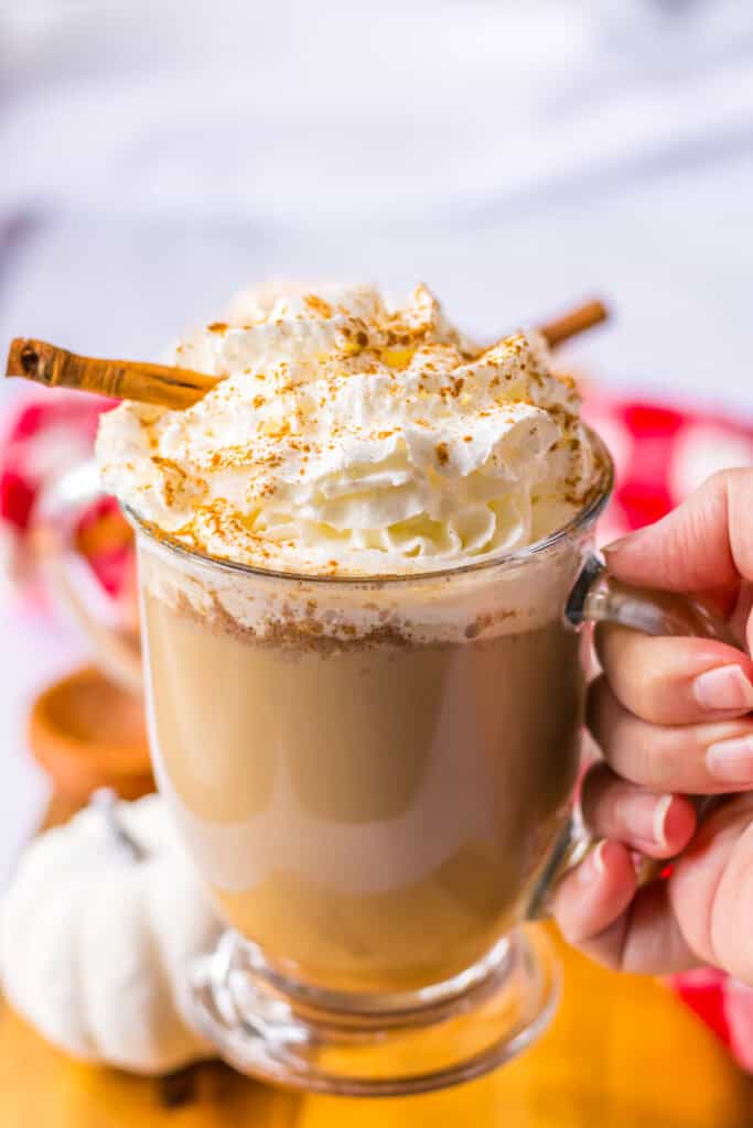 Hand holding Pumpkin Spice Latte in glass mug