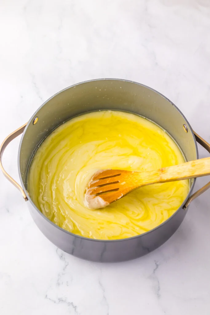 melted white chocolate in saucepan wooden spoon