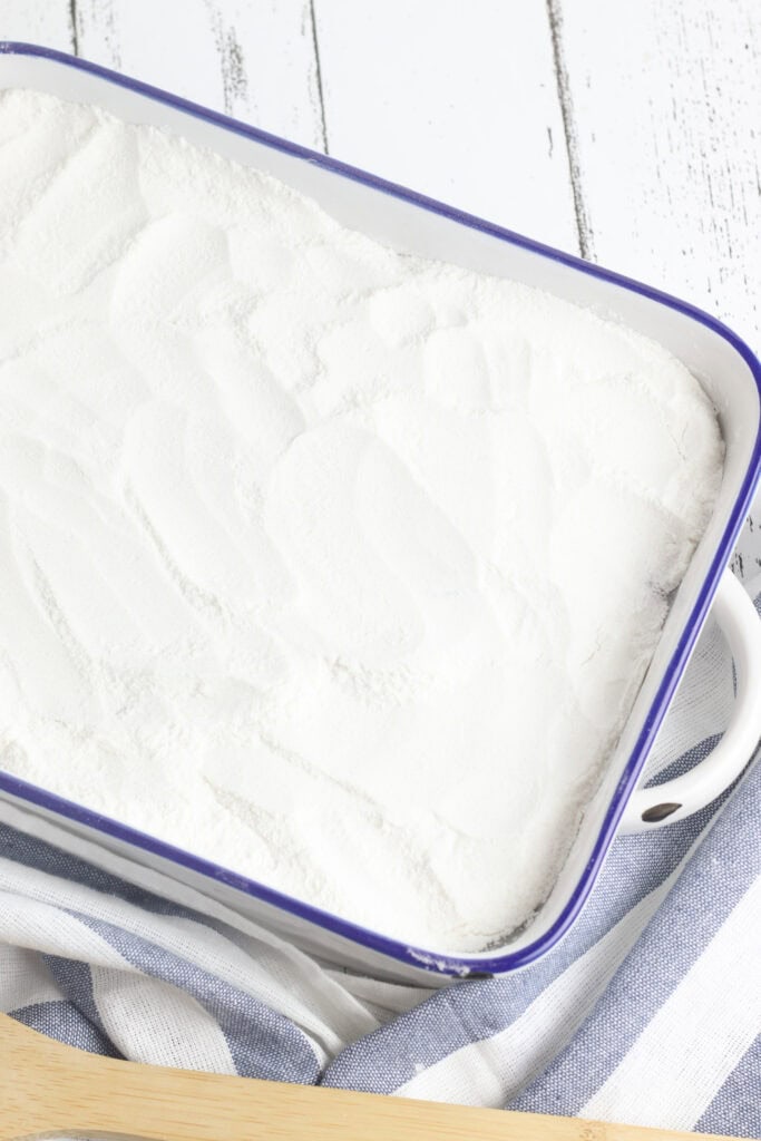 A baking dish filled with peaches covered by cake mix.