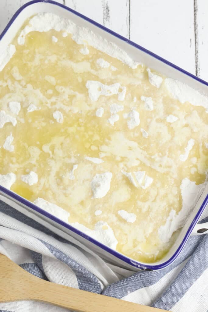 A casserole dish with peaches, cake mix and melted butter