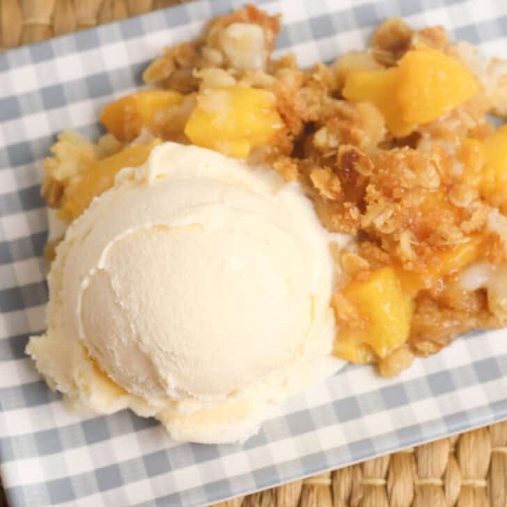 A plate with a peach crisp and ice cream.