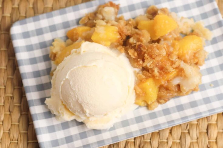 A plate with a peach crisp and ice cream.
