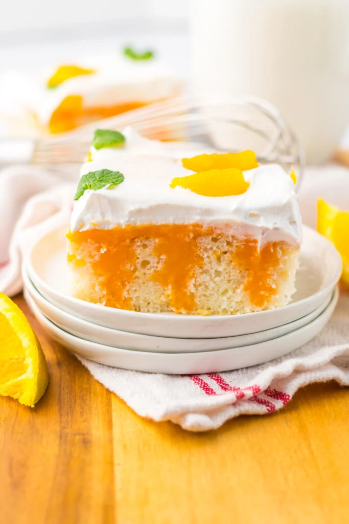 slice of Orange Creamsicle Poke Cake on white plate
