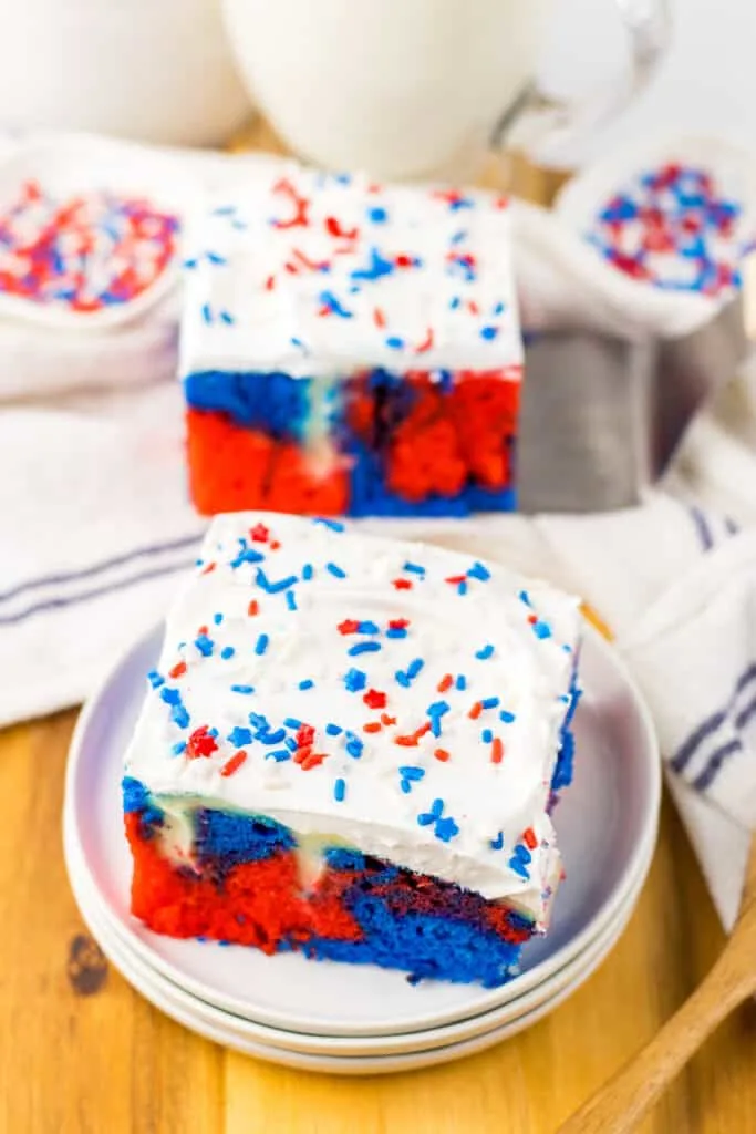 2 slices of red white and blue poke cake on white plates