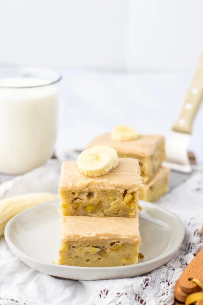 sliced banana bars on white plate, glass milk