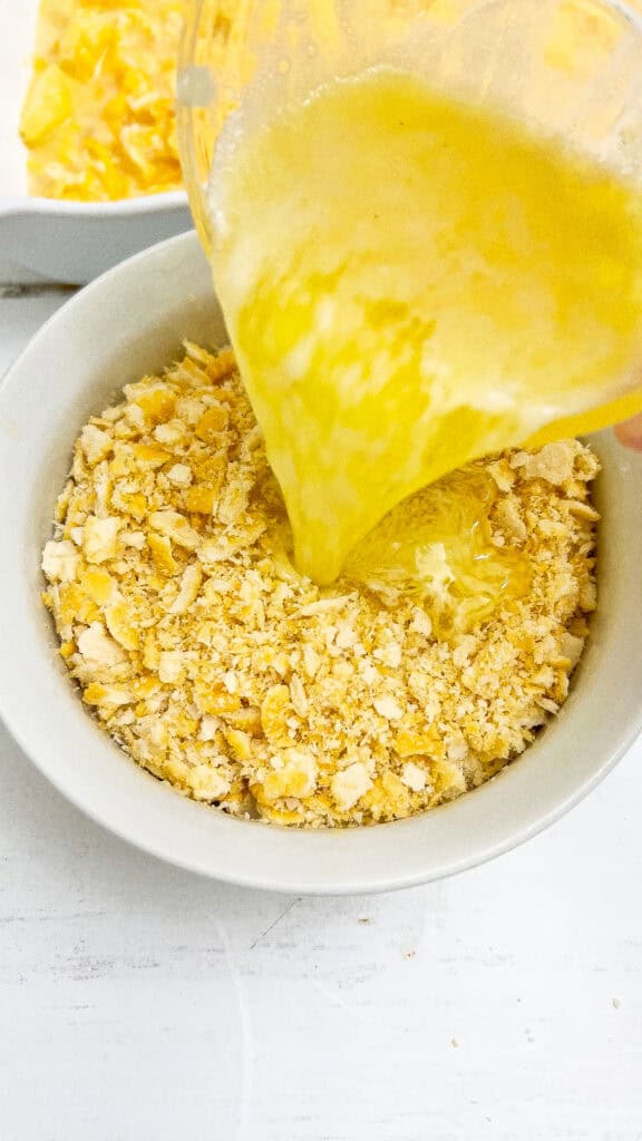 Pouring the melted butter into the bowl with casserole ingredients.