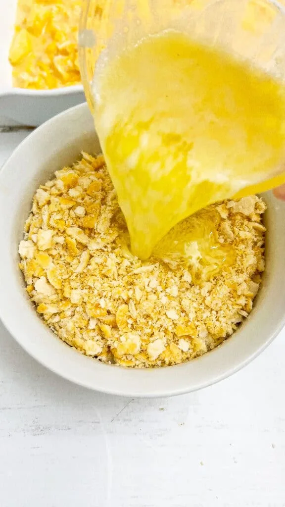 Pouring the melted butter into the bowl with casserole ingredients.