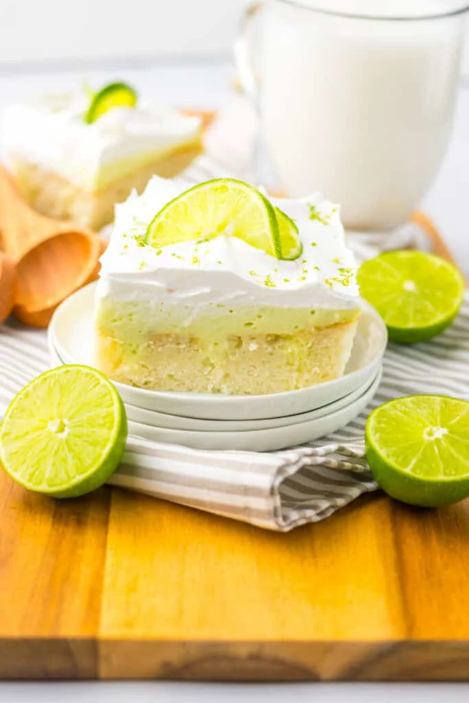 slice of poke cake on white plates and key limes