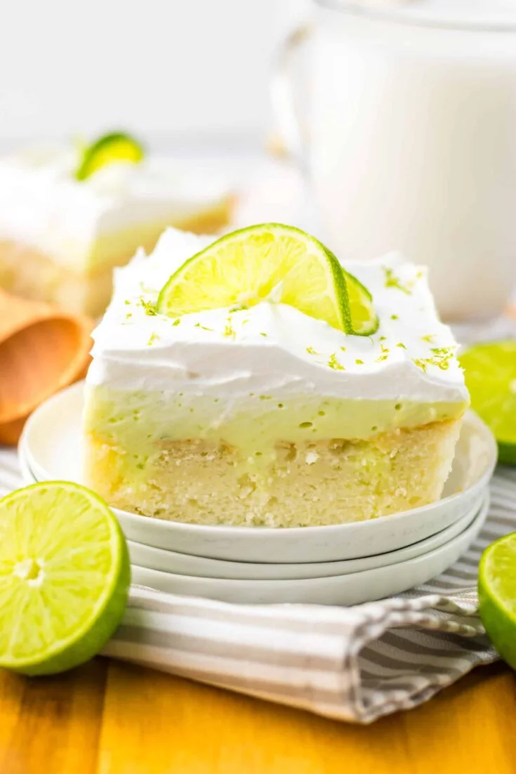 A slice of key lime pie on a plate with a glass of milk.