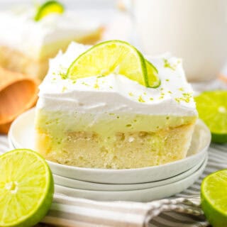 A slice of key lime poke cake on a plate with a glass of milk.