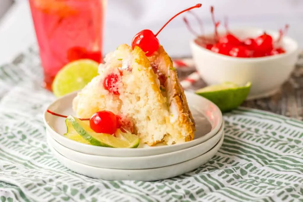 Fluffy cake with cherries and lime slices topped with cherry garnishes; perfect for tropical desserts.
