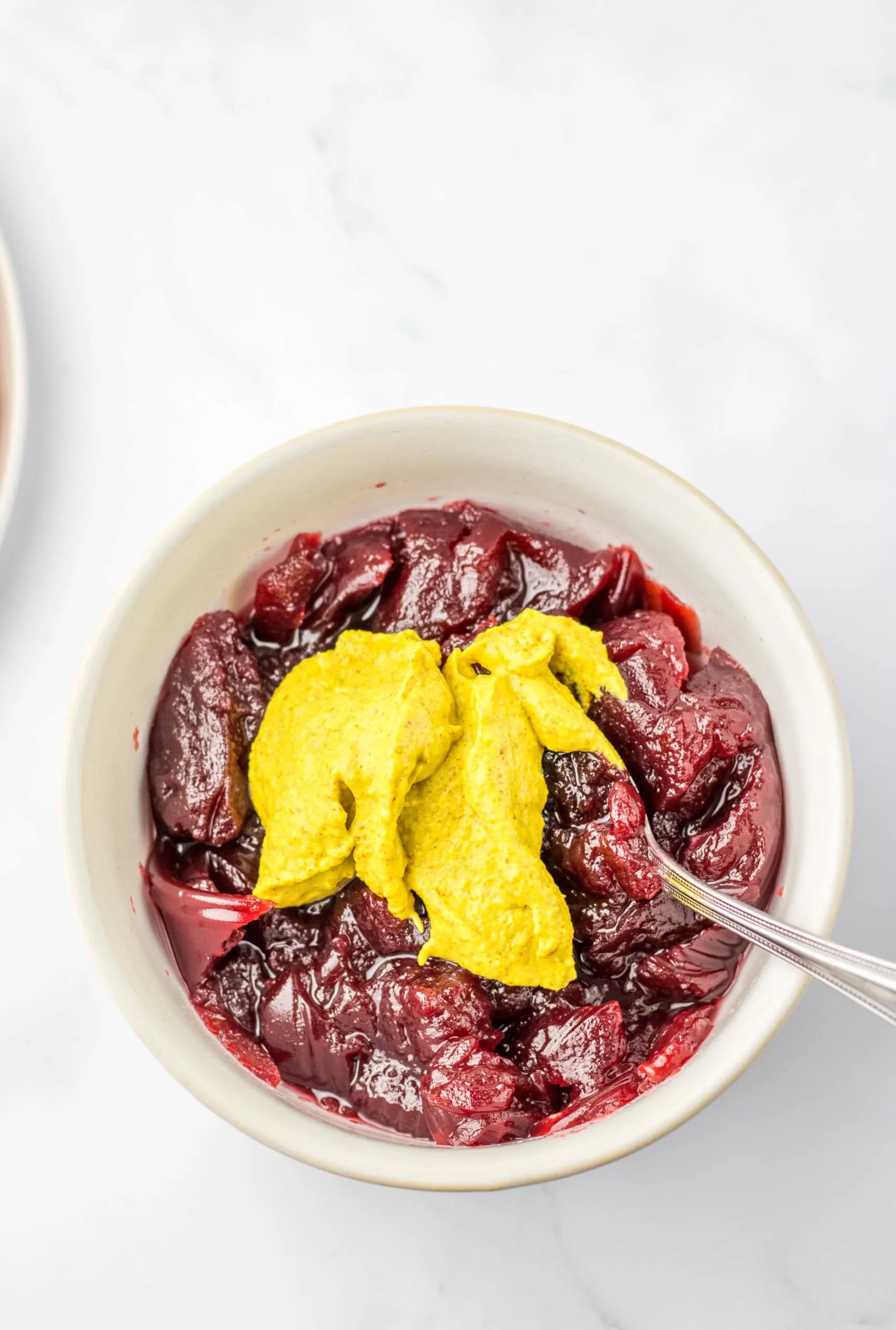 Cranberry and mustard sauce in a white bowl with a silver spoon, fresh fruit dessert, homemade cherry filling recipe, vibrant red, fresh ingredients, dessert idea, Moore or Less Cooking.