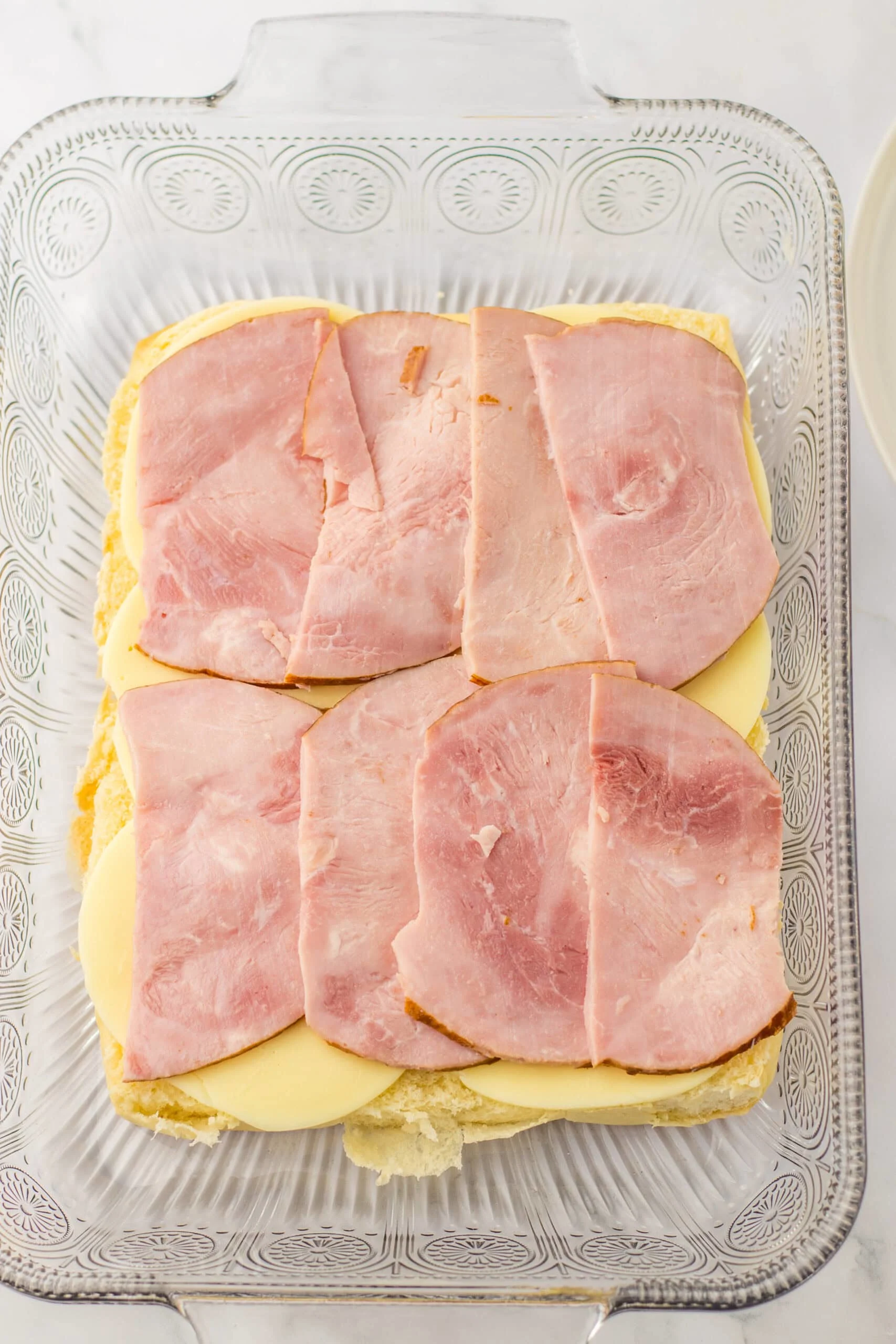Sliced ham and cheese on a casserole dish for a delicious ham and cheese casserole recipe. Perfect for family dinners and holiday meals.